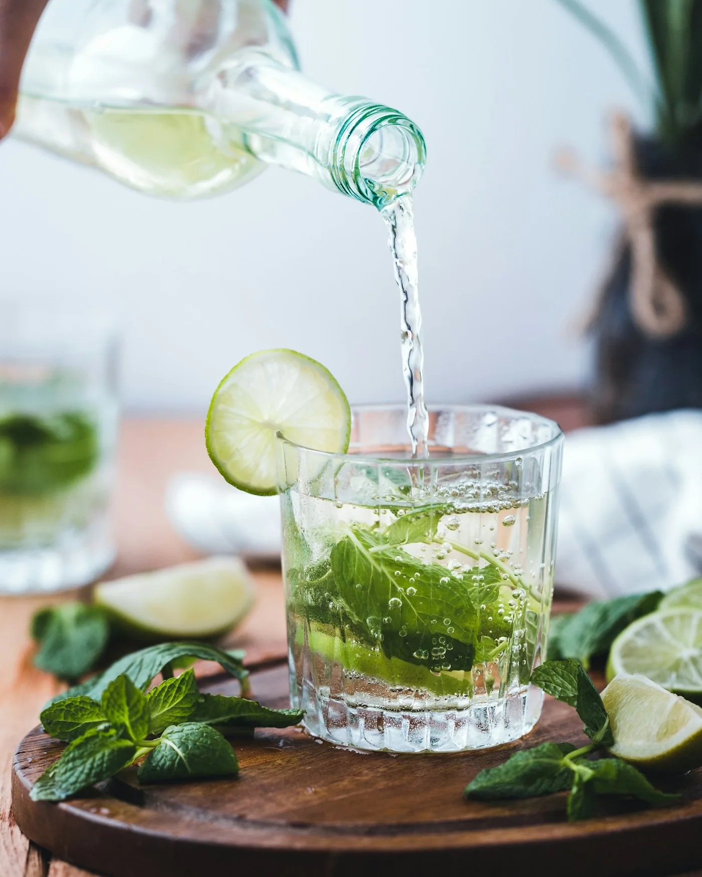 A mojito being poured over ice, mint and lime